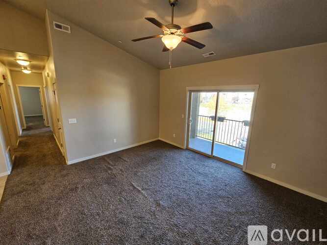 A spacious room with a ceiling fan and sliding glass doors leading to a balcony.