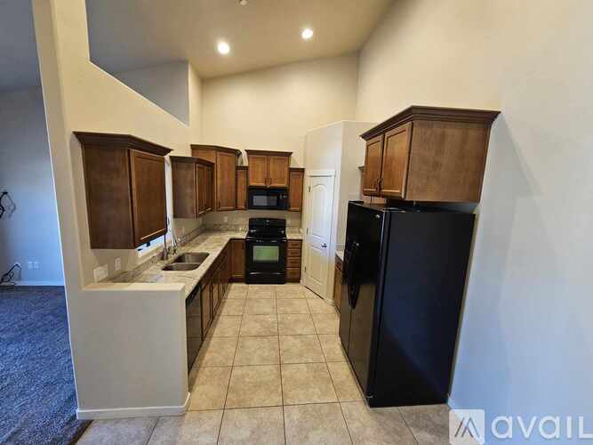 A kitchen with a black refrigerator and wooden cabinets.