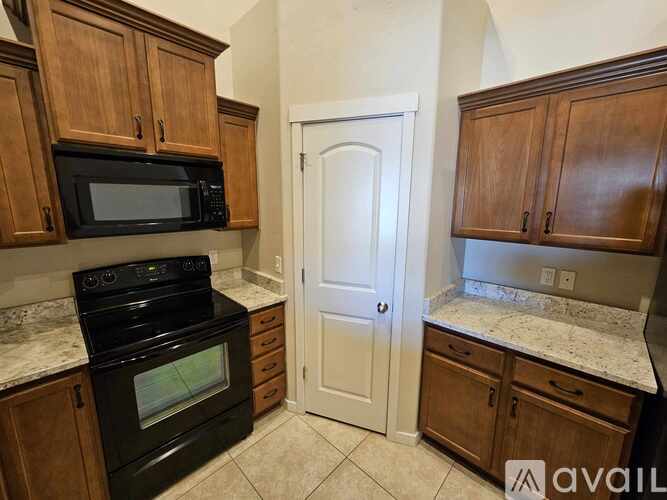 A kitchen with wooden cabinets and a black microwave above the stove.
