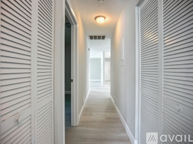 A long white hallway with a light on the ceiling.