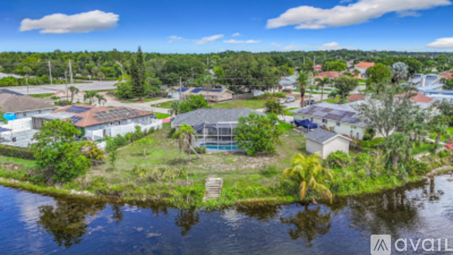 A bird's eye view of a residential area with houses, trees, and a body of water.