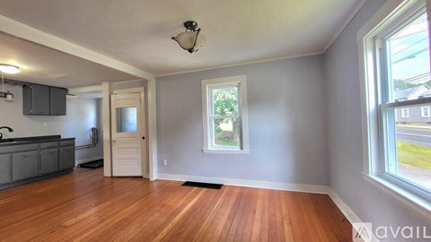 A room with wooden floors and a window showing greenery outside.