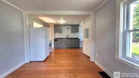 A kitchen with white appliances and wooden floors.