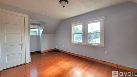 A room with wooden floors and a window showing trees outside.