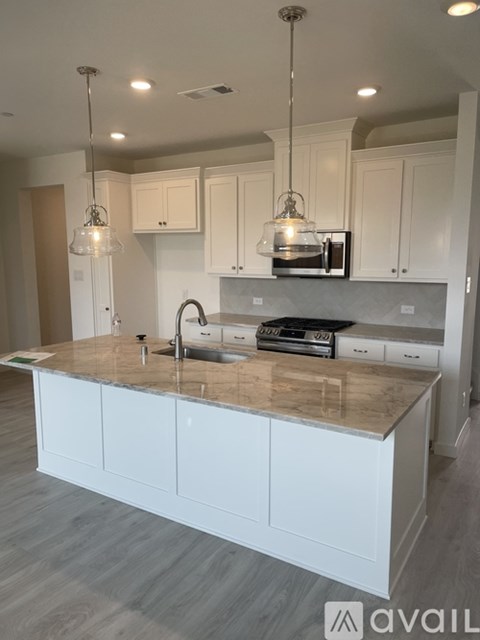 A modern kitchen with a marble countertop and white cabinets.