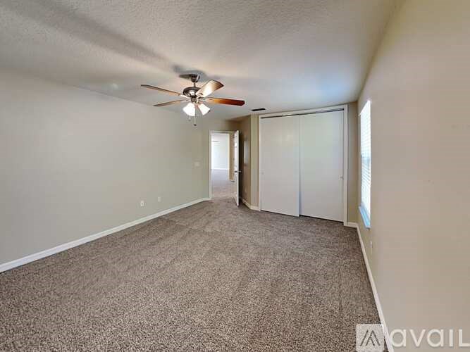 A room with a carpeted floor and a ceiling fan.