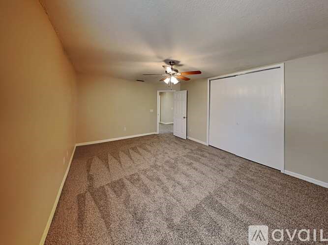 A room with a carpeted floor and a ceiling fan.