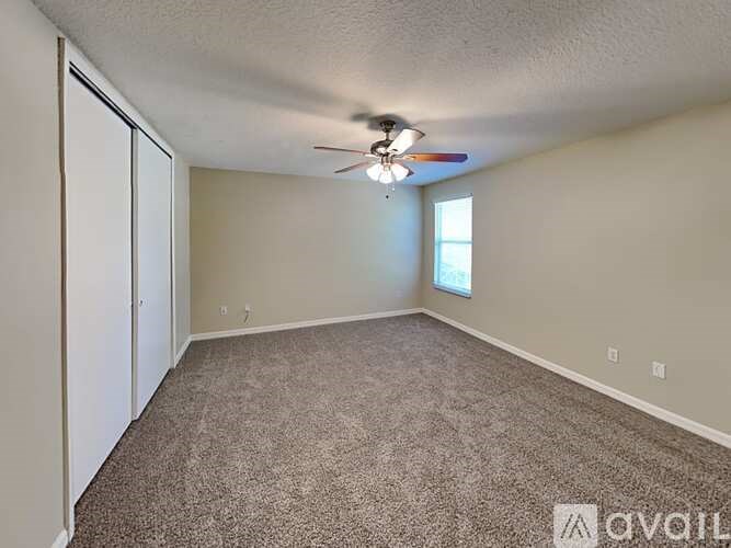 A room with a ceiling fan and carpeted floor.