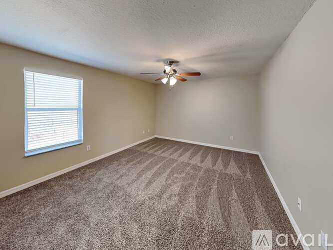 A room with a carpeted floor and a ceiling fan.