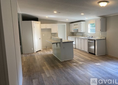 A kitchen with white cabinets and a wooden floor.