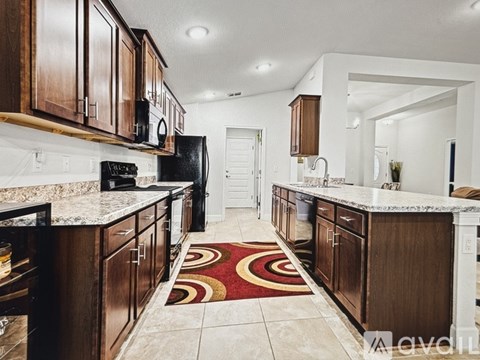 A kitchen with brown cabinets and a black refrigerator.
