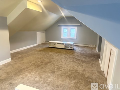 A room with a carpeted floor and a window with blinds.