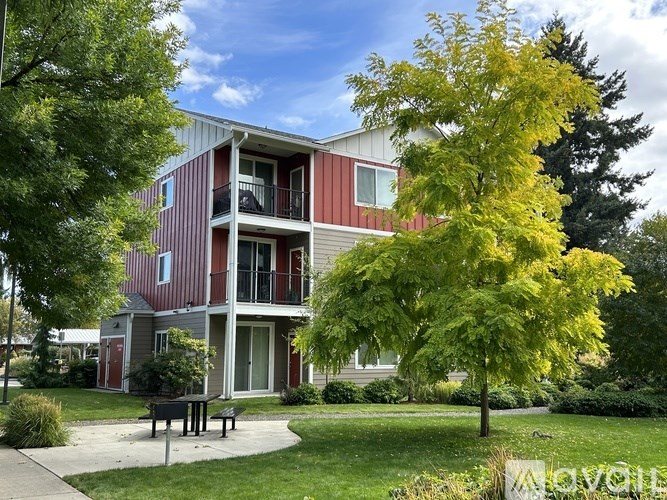 A red and white building with a balcony and a tree in front.