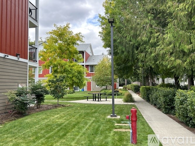 A red fire hydrant sits on a sidewalk next to a grassy area.