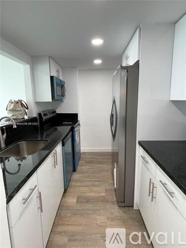 A kitchen with white cabinets and a black countertop.
