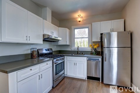 A kitchen with white cabinets and a stainless steel refrigerator.