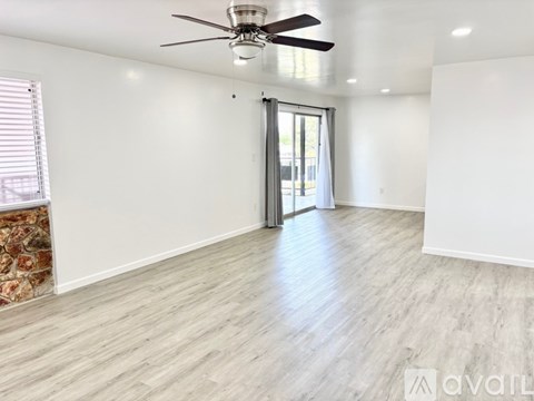 A spacious room with a ceiling fan and sliding glass door.
