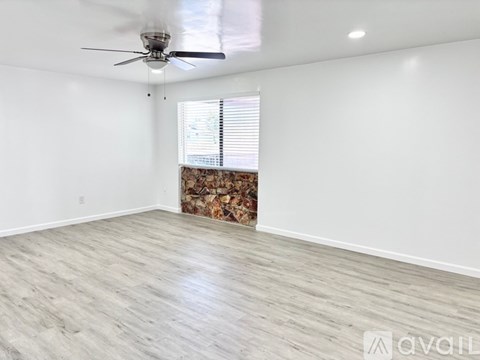 A room with a ceiling fan and a window with blinds.