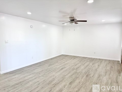 A spacious room with a ceiling fan and lighting fixtures.