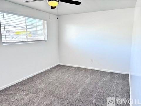A room with a ceiling fan and a window with blinds.