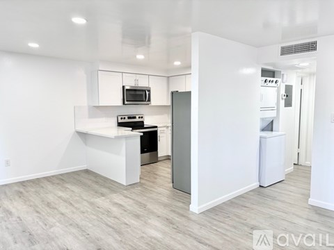 A modern kitchen with white cabinets and a flat screen TV mounted above the stove.