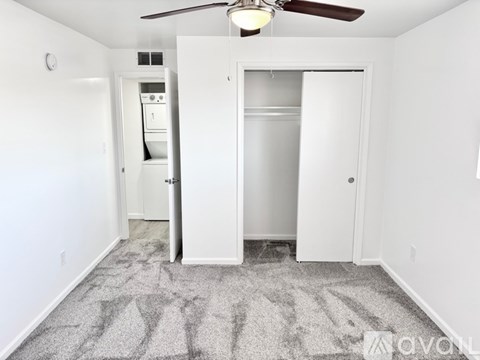 A room with a carpeted floor and a ceiling fan.