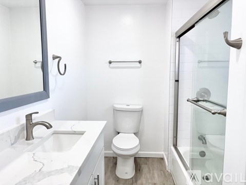 A white bathroom with a toilet, sink, and shower.