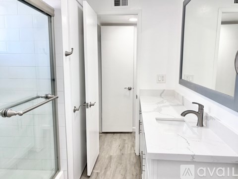 A white bathroom with a glass shower door and a white sink.