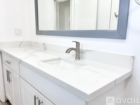 A bathroom with a white countertop and a silver faucet.