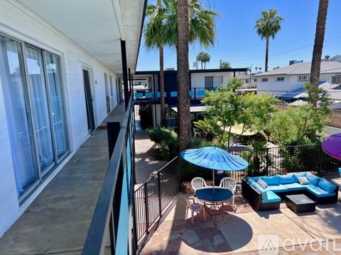 A balcony with a table and chairs and umbrellas.
