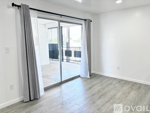 A room with a sliding glass door and grey curtains.