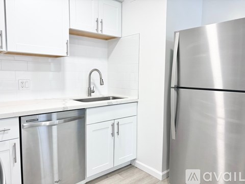 A modern kitchen with white cabinets and a stainless steel refrigerator.