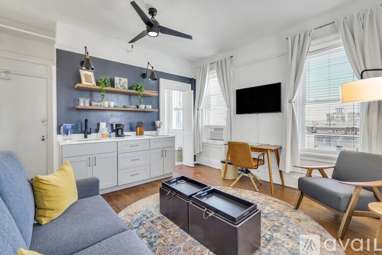 A living room with a grey sofa, a coffee table, and a flat screen TV mounted on the wall.