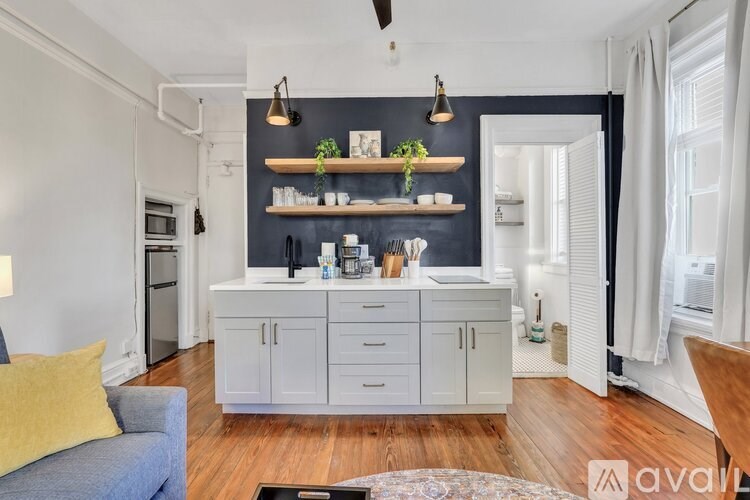 A modern kitchen with white cabinets and a blue couch.