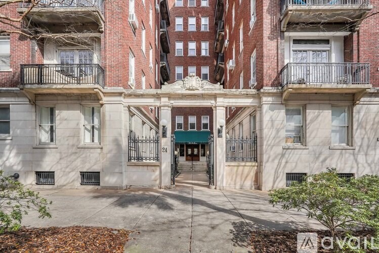 A building with a balcony and a green awning is in front of a brick building.