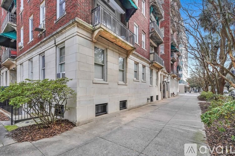 A street view of a row of apartment buildings with a sidewalk and trees.