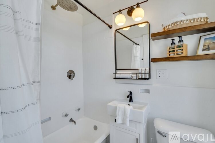A bathroom with a white shower curtain, a white sink, and a mirror above it.