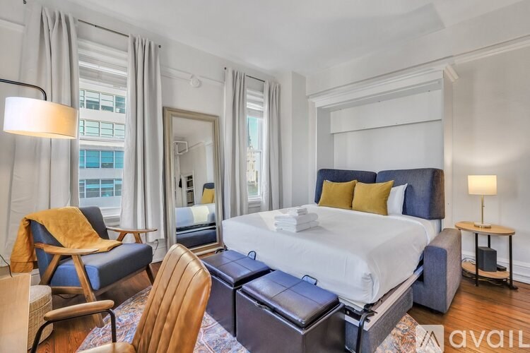 A bedroom with a large bed, a chair, and a table.