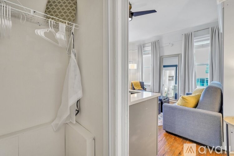 A white laundry room with a hanging towel and a view into the living room.