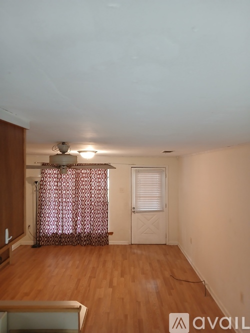 A room with wooden floors and a patterned curtain.