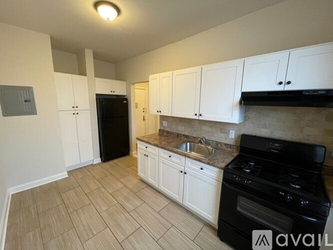 A kitchen with white cabinets and a black stove top oven.