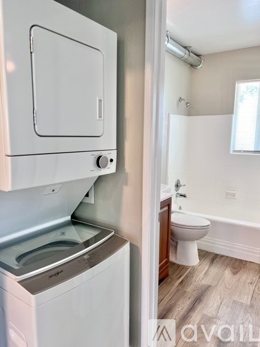 A white dishwasher is next to a white toilet in a small bathroom.