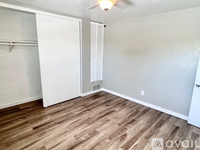 A room with a white door and a wooden floor.