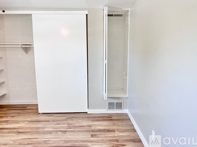 A white door with a glass panel is open in a room with wooden flooring.