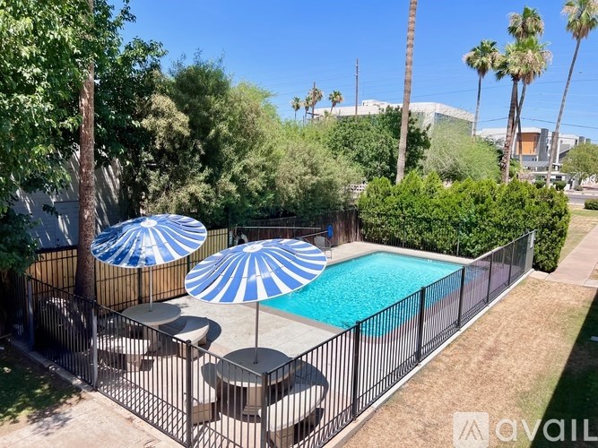 A pool surrounded by a black fence with blue and white striped umbrellas.
