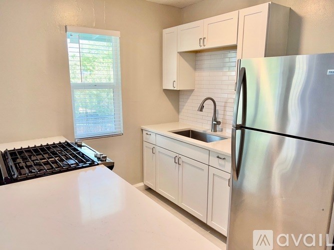 A kitchen with a stove, sink, and refrigerator.
