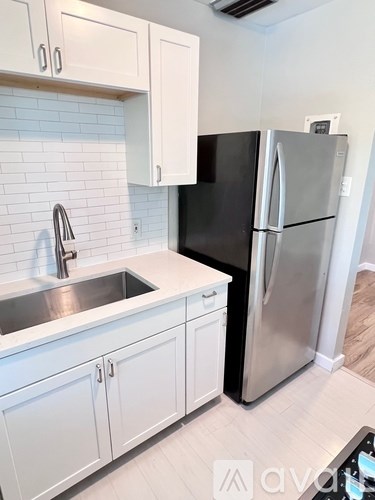 A kitchen with a black refrigerator and white cabinets.