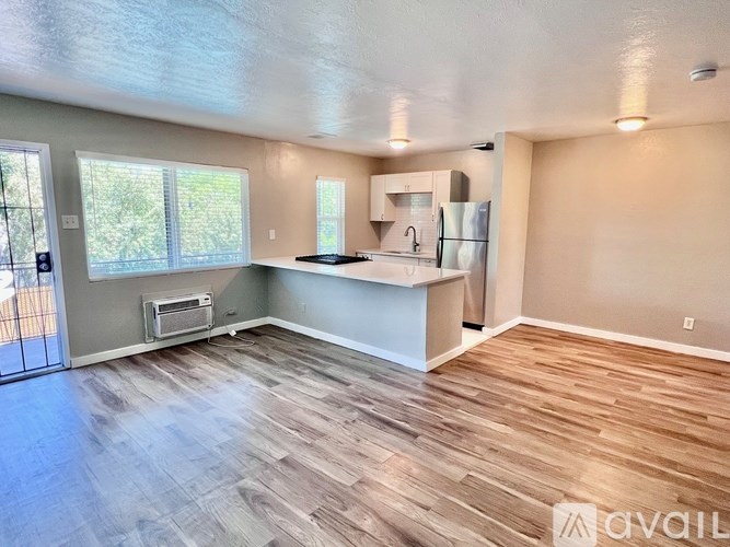 A kitchen area with wood flooring and a refrigerator.