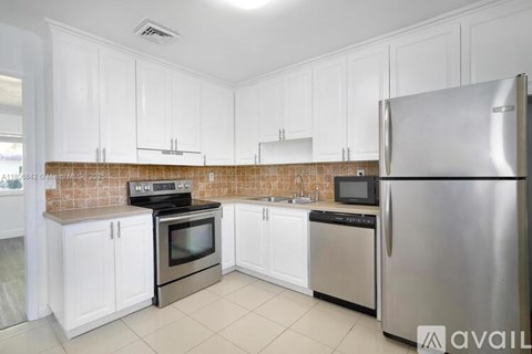 A kitchen with white cabinets and a stainless steel refrigerator.