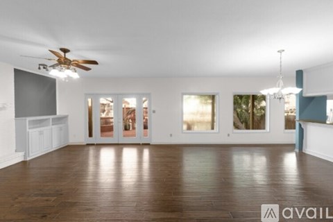 A spacious room with wooden floors and a ceiling fan.